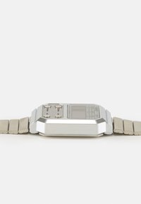 Montre numérique en acier inoxydable argenté avec un boîtier angulaire, plusieurs boutons et un bracelet à maillons. Profil slim, écran rectangulaire et matériel minimal.