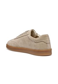 Zapatillas de ante beige con un perfil bajo, punta redonda y suela de goma marrón. Presentan cordones en tonalidad similar y un cuello acolchado.