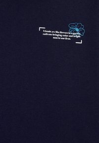 T-shirt in cotone blu navy con testo bianco che recita: "Gli amici sono come fiori in un giardino", accompagnato da un grafiche di un fiore blu sopra.