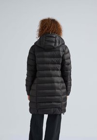 Cappotto imbottito nero con cappuccio, caratterizzato da un design trapuntato e cuciture verticali, di lunghezza media e una texture liscia e lucida.