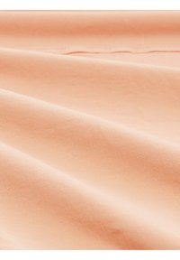 Tissu en coton pêche au texture lisse, avec des lignes subtiles et un drapé doux. La surface présente un léger éclat sous la lumière.