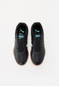Zapatillas deportivas negras con parte superior sintética texturizada, cordones negros y acentos turquesa. Presenta una suela de goma y un logo blanco de Puma.