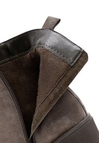 Brown suede ankle boot with a black leather trim, zipper closure, and soft lining. Features a sturdy sole and subtle stitching details.