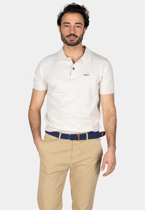 Hellbeige Poloshirt mit kurzen Ärmeln, geknöpftem Kragen und grünen/blauen Knöpfen. Kombiniert mit khakifarbenen Hosen und einem blauen gewebten Gürtel.