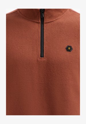 Rits-fleece pullover in roestkleur, met een textielstof, hoge kraag en zwarte rits. Klein zwart hexagonaal logo op de borst.
