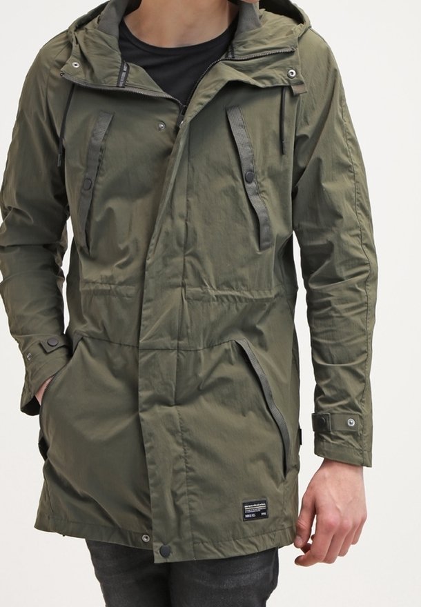 Parka verde oliva con cappuccio, chiusura frontale con zip, due tasche sul petto e tasche laterali. Realizzata in materiale leggero, presenta chiusure a scatto e a zip.