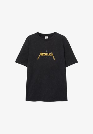 Black oversized t-shirt made of cotton, featuring a distressed texture and a yellow "METALLICA" logo printed at the center.