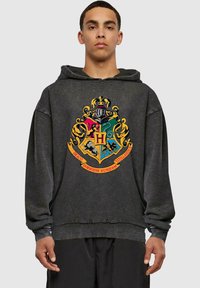 Sudadera de un gris oscuro hecha de tela suave, que presenta un gran diseño de escudo colorido con una "H" central y acentos dorados en la parte frontal.