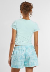 Lys blå tettsittende t-skjorte med korte ermer, parret med mønstrede lys blå shorts med elastisk midjebånd og intrikat design.