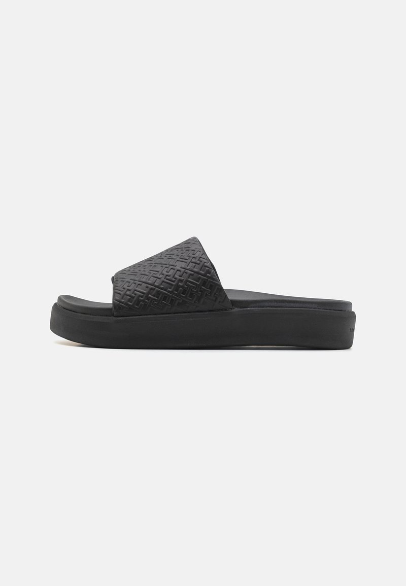 Sort slidesandal med en tekstureret overdel med et geometrisk mønster, en flad sål og et glat, fleksibelt materiale for komfort.