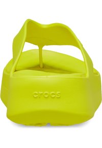 Sandales en caoutchouc jaune vif au design minimaliste, dotées d'une sangle arrière, d'une semelle texturée et d'un logo en relief sur le côté.