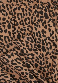 Luipaardprint stof in bruine en zwarte tinten, met een zachte textuur, geplooid ontwerp en zichtbare stiksels.