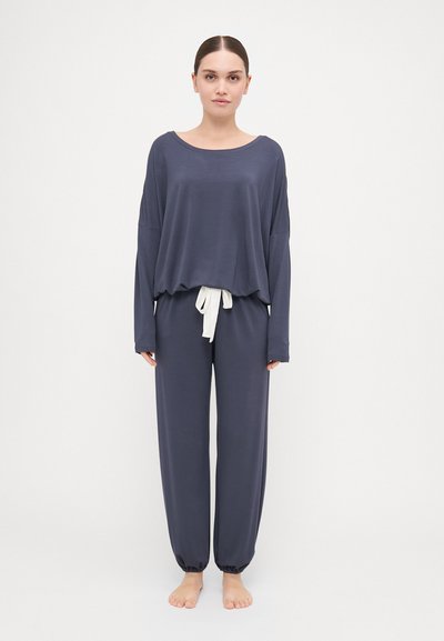Navy long-sleeve top with wide neckline and loose fit, paired with matching pants featuring an elastic waistband and white drawstring.