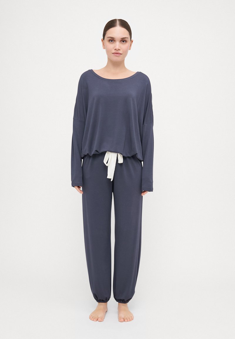 Navy long-sleeve top with wide neckline and loose fit, paired with matching pants featuring an elastic waistband and white drawstring.