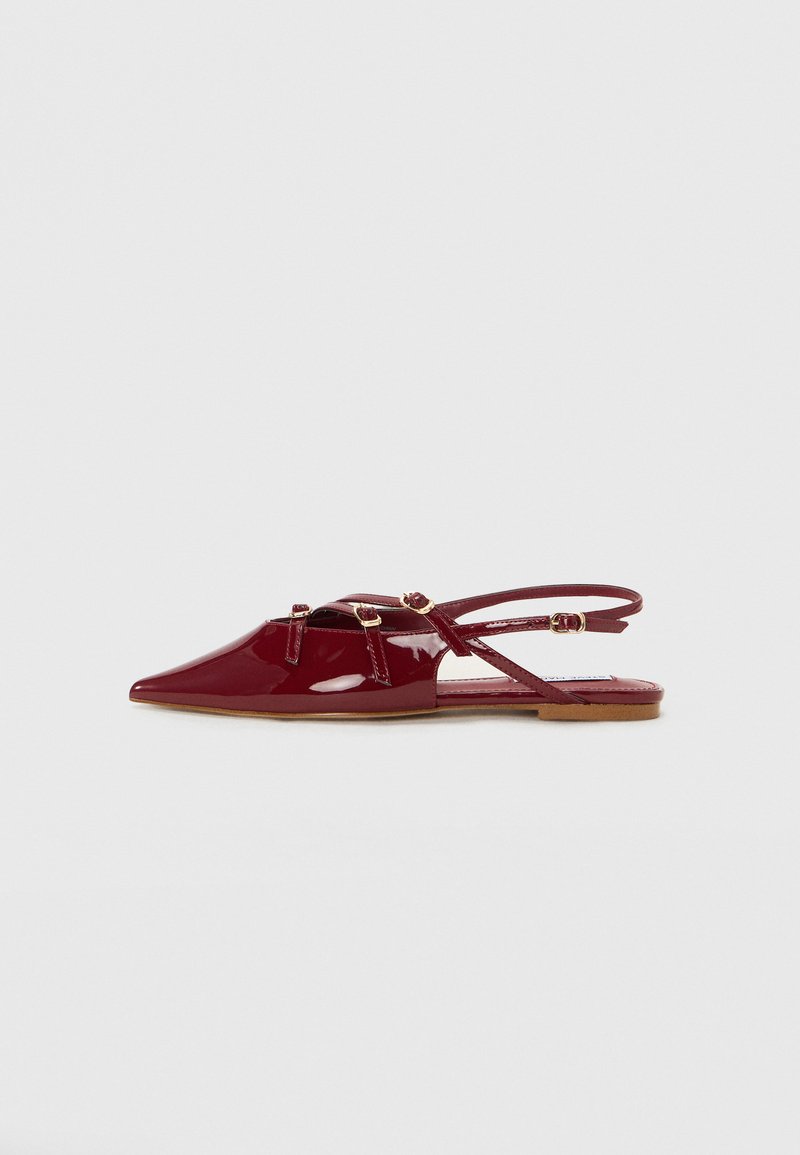 Chaussure slingback en cuir verni rouge avec un bout pointu, dotée de fines lanières et d'accents en matériel doré. Semelle plate avec une finition lisse.