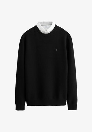 Zwarte gebreide trui met een ribbelstructuur. Voorzien van een ronde hals en een witte overhemdondergrond. Klein logo geborduurd op de borst.