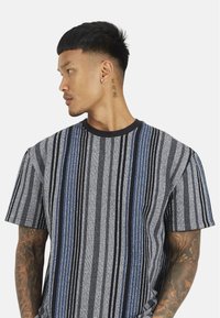 Koszulka z krótkim rękawem w paski, łącząca odcienie niebieskiego, szarego i czarnego, z okrągłym dekoltem i teksturowanym materiałem.