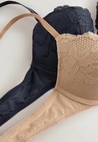 Twee beha's in marineblauw en nude kleuren. Beiden hebben bloemenkant overlays, mesh stof en gladde bandjes met gestikte randen.