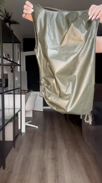Šaty bez rukávov v olivovo zelenej farbe vyrobené z lesklého, hladkého materiálu s jemne zvrásnenou textúrou a s okrúhlym výstrihom, vystavené na neutrálnom pozadí.