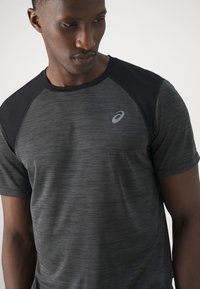 Black and grey athletic t-shirt with a textured pattern, featuring raglan sleeves and a subtle logo on the chest. Made of breathable fabric.