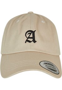 Beige színű, pamut anyagú baseball sapka ívelt lefedéssel, az elején fekete hímzett "A" betűvel és állítható hátsó pánttal.