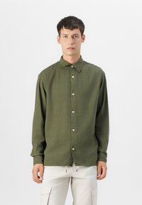 Olive green long-sleeve shirt with a textured fabric, button front, and pointed collar. Simple, relaxed fit with straight hem.