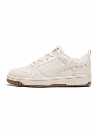 Jasnobeżowy niski sneaker z zapięciem na sznurowadła, perforowanym obszarem palców, teksturowanymi panelami po bokach i brązową gumową podeszwą.