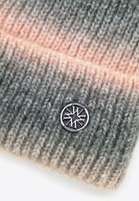 Dzianinowa czapka typu beanie w gradientowych odcieniach szarości i beżu z teksturowaną włóczką. Zdobiona okrągłym metalicznym logo.