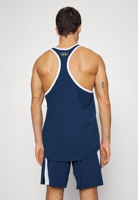 Granatowy top bez rękawów z białymi wykończeniami i żółtym logo. Posiada plecy w stylu racerback oraz zaokrąglony dół, wykonany z miękkiego, oddychającego materiału.