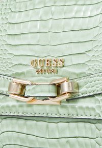 Borsa a tracolla in pelle verde strutturata con un motivo a croco in rilievo. Presenta metalleria dorata e una placca con logo sulla parte frontale.