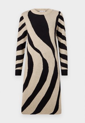 Gebreide jurk met een beige basis en opvallende zwarte zebraprints, lange mouwen en een ronde halslijn. Zachte textuur met een relaxed fit.
