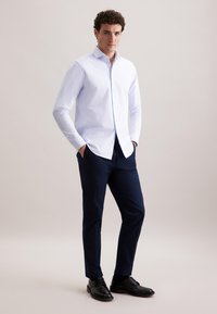 Lichtblauwe button-up shirt met lange mouwen, gecombineerd met marineblauwe broek en zwarte schoenen. Eenvoudig ontwerp, mooie textuur en op maat gemaakte pasvorm.