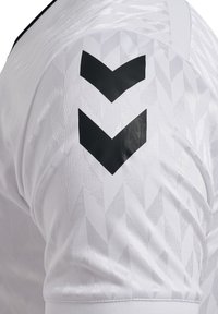 Maglia sportiva bianca con un motivo a diamante testurizzato. Presenta accenti neri a forma di chevron sulle spalle. Realizzata in materiale leggero e traspirante.