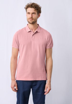 Roze katoenen polo met kraag, twee knopenlijst, korte mouwen en een subtiele logo-detail op de linkerkant van de borst. Gemaakt met marineblauwe broek.
