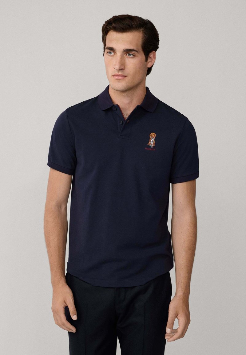 Marinblå polo skjorta i bomull med krage med två knappar, med en liten broderad logotyp på bröstet och uppvikt ärmar.