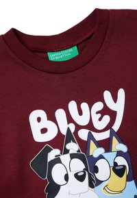 Bordeauxroter Baumwollpullover mit Cartoon-Figuren und dem weißen Schriftzug "BLUEY". Rundhalsschnitt, glatte Oberfläche, mit lebendigen Druckdetails.