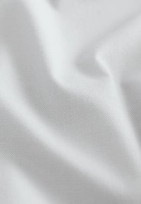 Witte stof met een glad, lichtelijk gestructureerd oppervlak, voorzien van fijne, gelijkmatige weefpatronen en zachte plooien.