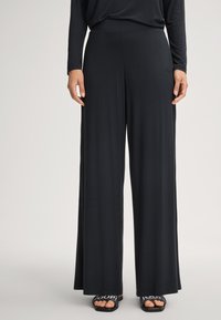 Schwarze weit geschnittene Hose aus weichem, leichtem Stoff, mit einem glatten Bund und einem dezenten Designdetail nahe der Hüfte.