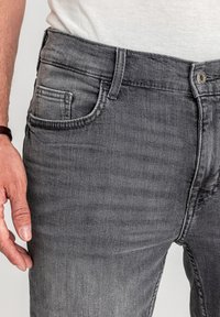 Szare jeansy z denimu o klasycznym kroju z pięcioma kieszeniami, z delikatnymi wyblaknięciami i dopasowanym fasonem. Zapięcie na guzik i zamek błyskawiczny.