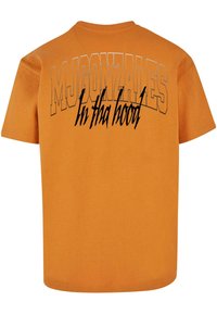 Oransje bomull T-skjorte med fet trykt tekst "MJ GONZALES" og "In tha hood" i svart med teksturert finish. Kortermet og rundhalsdesign.