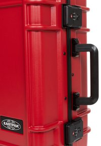 Red hard-shell suitcase featuring a textured surface, locking mechanism, black handle, and Eastpak branding.