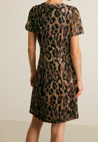 Vestido de estampado de leopardo con mangas cortas, un corpiño ajustado y una falda acampanada. El material tiene una textura suave con un ligero brillo.