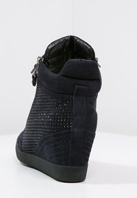 Sneaker compensée en daim bleu marine avec des détails cloutés et des accents texturés. Dotée d'une fermeture éclair et d'une semelle en caoutchouc noir pour une meilleure adhérence.