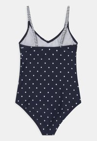 Marineblauer Einteiler-Badeanzug mit weißen Punkten, ausgestattet mit Mesh-Paneelen und verstellbaren gestreiften Trägern. Glatte Textur und taillierter Schnitt.