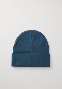Berretto in teal scuro realizzato in morbido materiale knit. Presenta una vestibilità aderente con un risvolto nella parte inferiore e una parte superiore arrotondata senza cuciture.