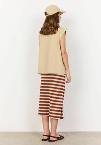 Beige sleeveless top with a loose fit, paired with a knee-length striped skirt in brown and cream. Includes a matching cap and flat sandals.