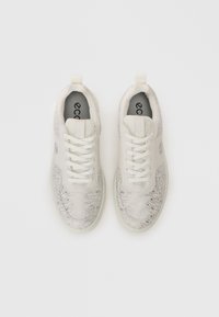 Un paio di sneakers bianche con lacci, caratterizzate da un sottile motivo topografico grigio, viste dall'alto su uno sfondo bianco uniforme.