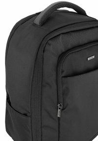 Czarny plecak z tkaniny z wyściełanym uchwytem, zapinaną na zamek kieszenią z przodu i gładką fakturą. Posiada subtelny detal logo oraz wzmocnione szwy.