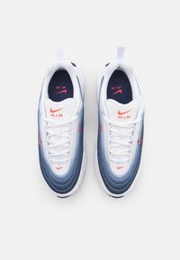 Nike Air sportbačiai su balta ir mėlyna gradientine viršūne, tekstūruotomis linijomis ir ryškiai raudonomis detalėmis. Viduje mėlynas interjeras ir balti raišteliai.