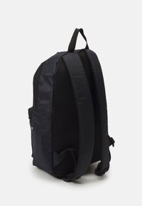 Zaino nero con spallacci imbottiti in rete. Esterno in tessuto liscio, forma arrotondata e tasca laterale per oggetti piccoli.